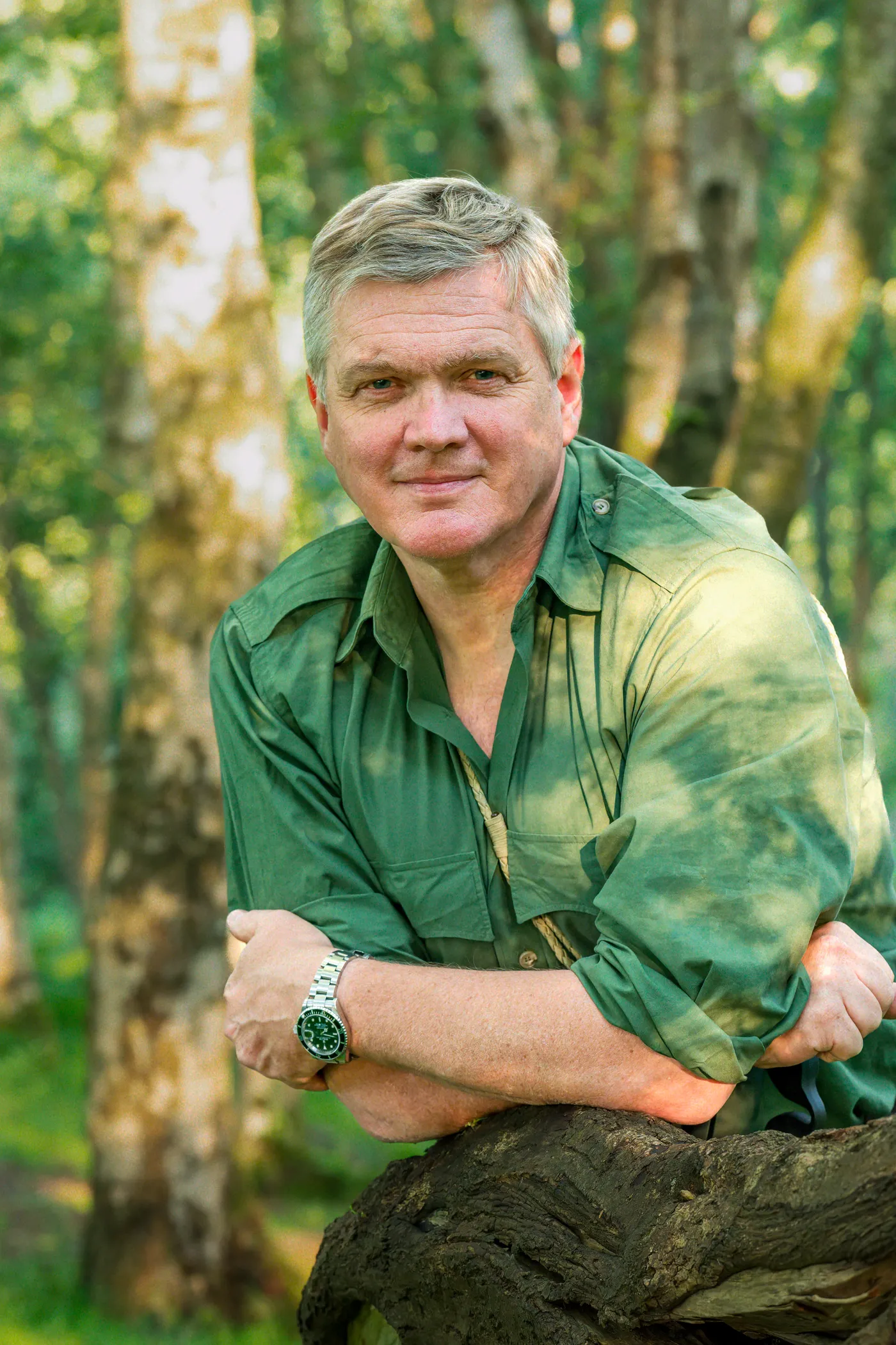 Ray Mears leaning on a fallen tree in woodland
