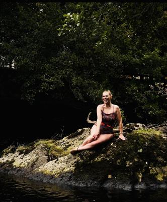 A woman sitting on rocks beside a river after open water swimming