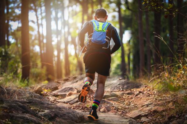 A trail runner making their way along a rocky woodland path